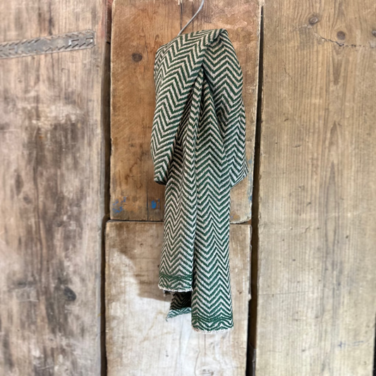 Green and white chevron-patterned garment hanging on a wooden door.